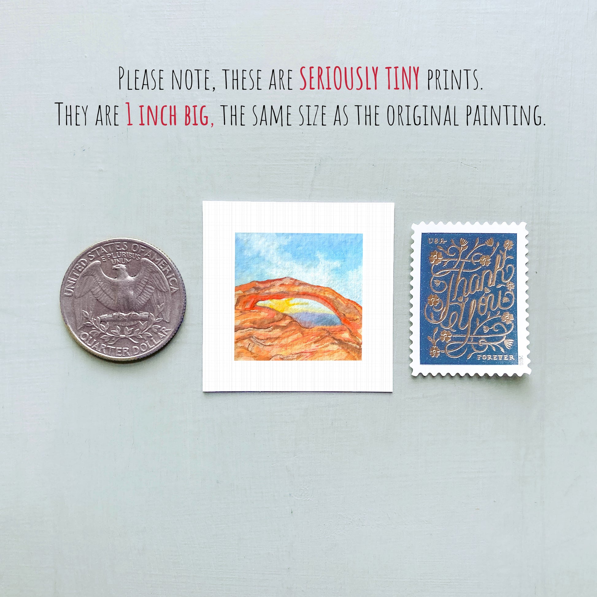 three small prints: a quarter, a postage stamp, and a painting of a mountain landscape.