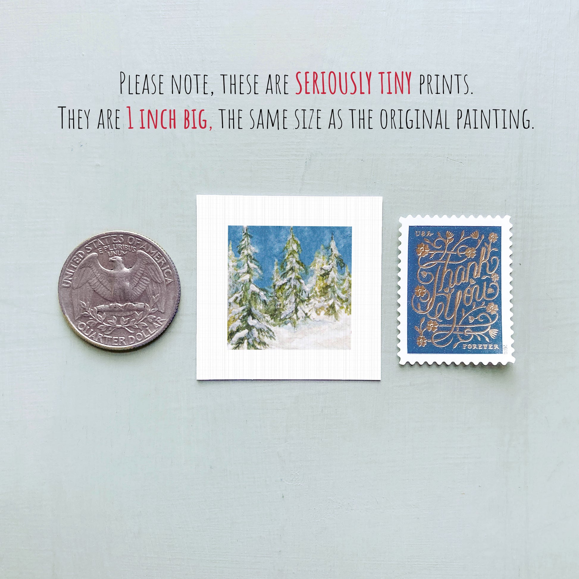 three small prints: a United States quarter, a square print of a snowy landscape, and a blue postcard with a gold design.