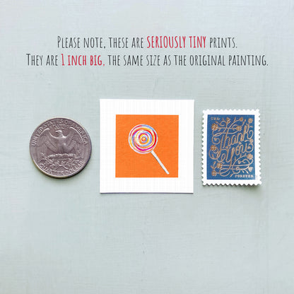 three small, tiny prints: a United States quarter, a small square print with an orange background and a lollipop illustration, and a blue postage stamp with gold lettering.