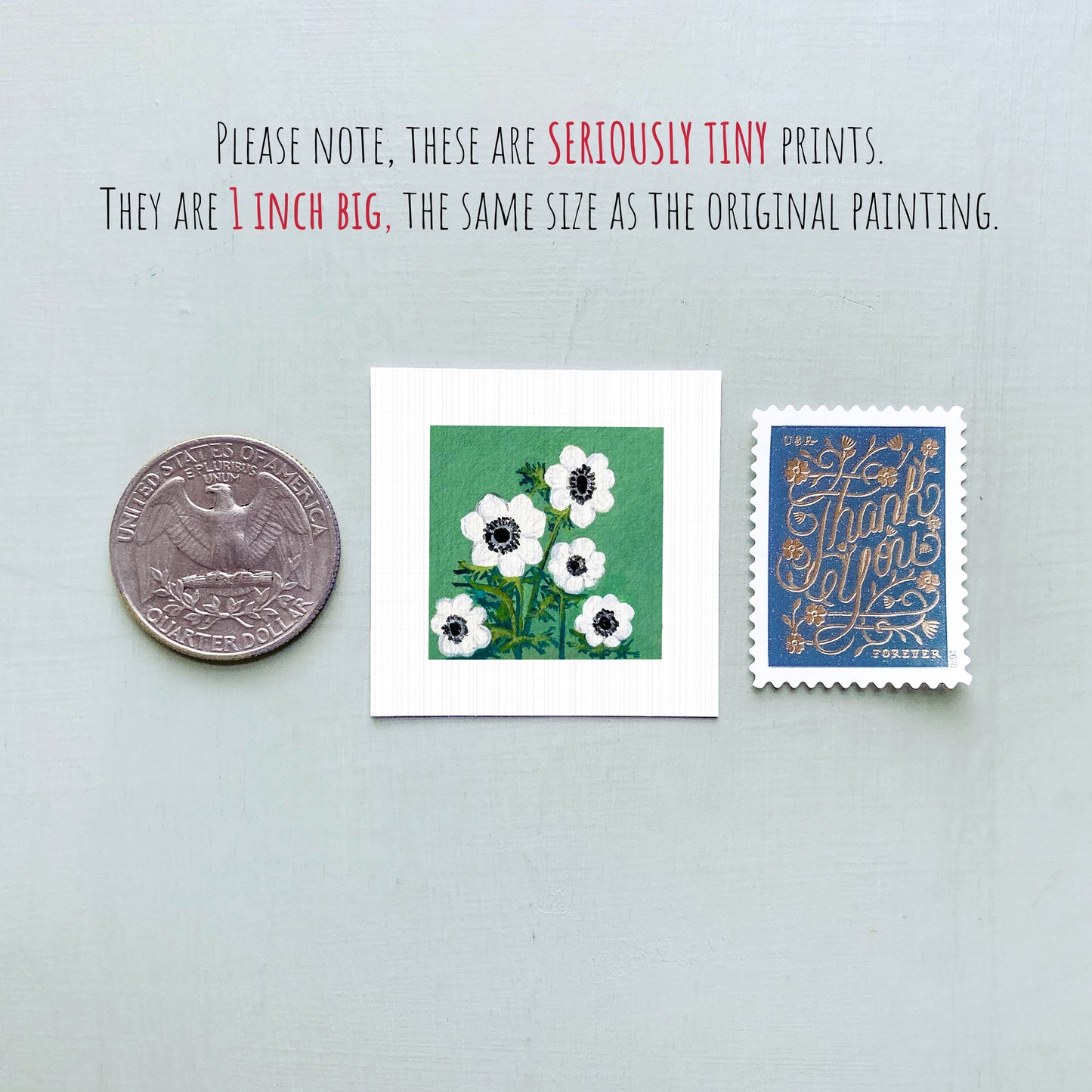 three small artworks: a silver coin, a square print of white flowers, and a blue postage stamp with gold lettering.
