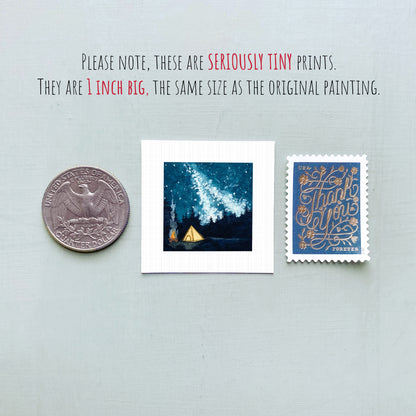 three small prints: a United States quarter, a square print of a night sky with a tent, and a blue postage stamp with gold lettering.