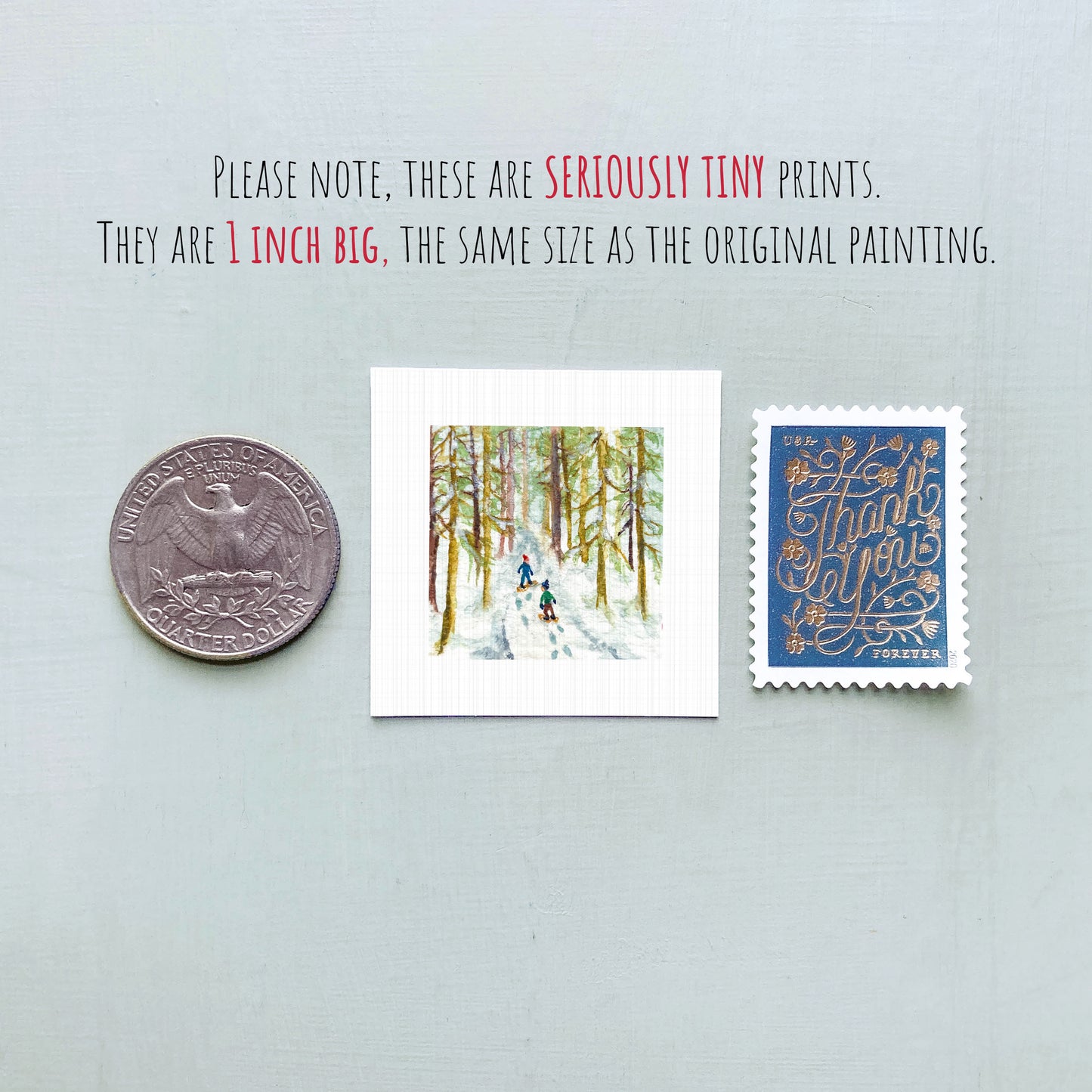 three small artworks or prints, including a coin, a postage stamp, and a painting of a snowy forest scene.