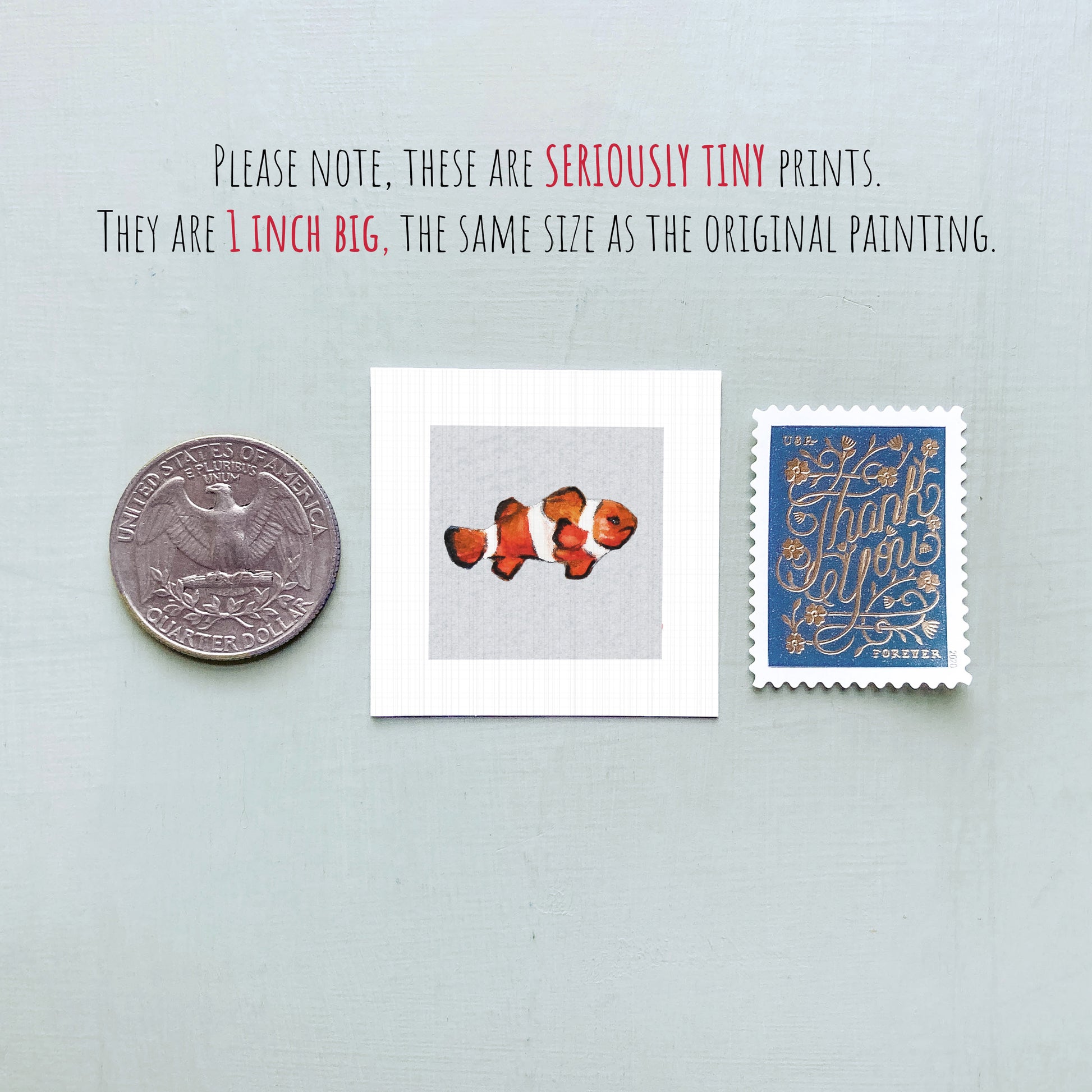three small items: a quarter, a square print of an orange fish, and a blue postage stamp.