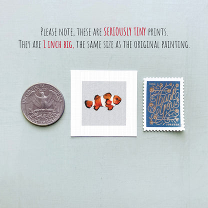 three small items: a quarter, a square print of an orange fish, and a blue postage stamp.