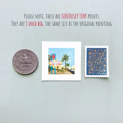 three small prints: a United States quarter, a miniature painting of Las Vegas, and a postage stamp.