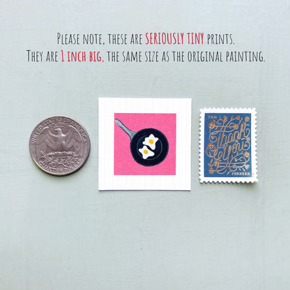 three small objects: a United States quarter, a square with a frying pan and eggs, and a blue postage stamp with gold lettering.