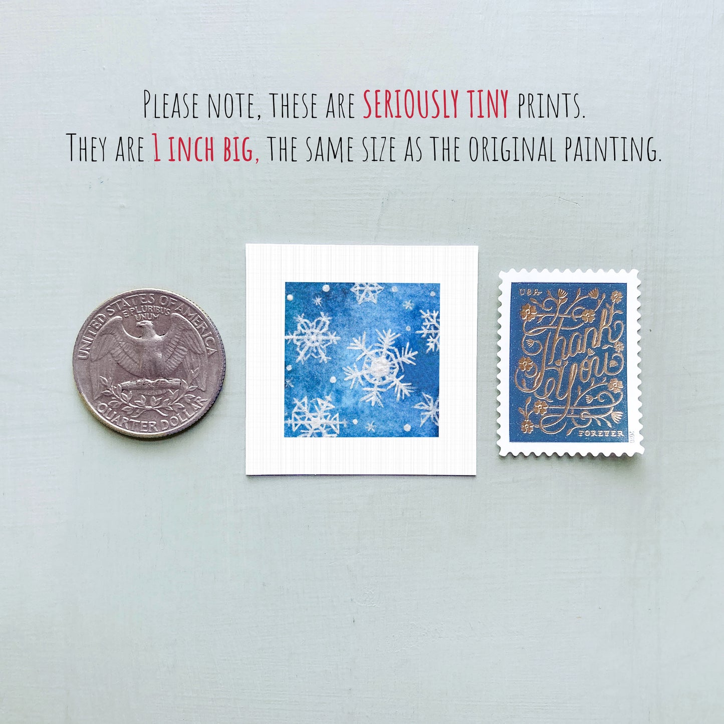 three small artworks: a silver coin, a blue square with white snowflakes, and a blue postage stamp with gold lettering.