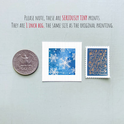 three small artworks: a silver coin, a blue square with white snowflakes, and a blue postage stamp with gold lettering.