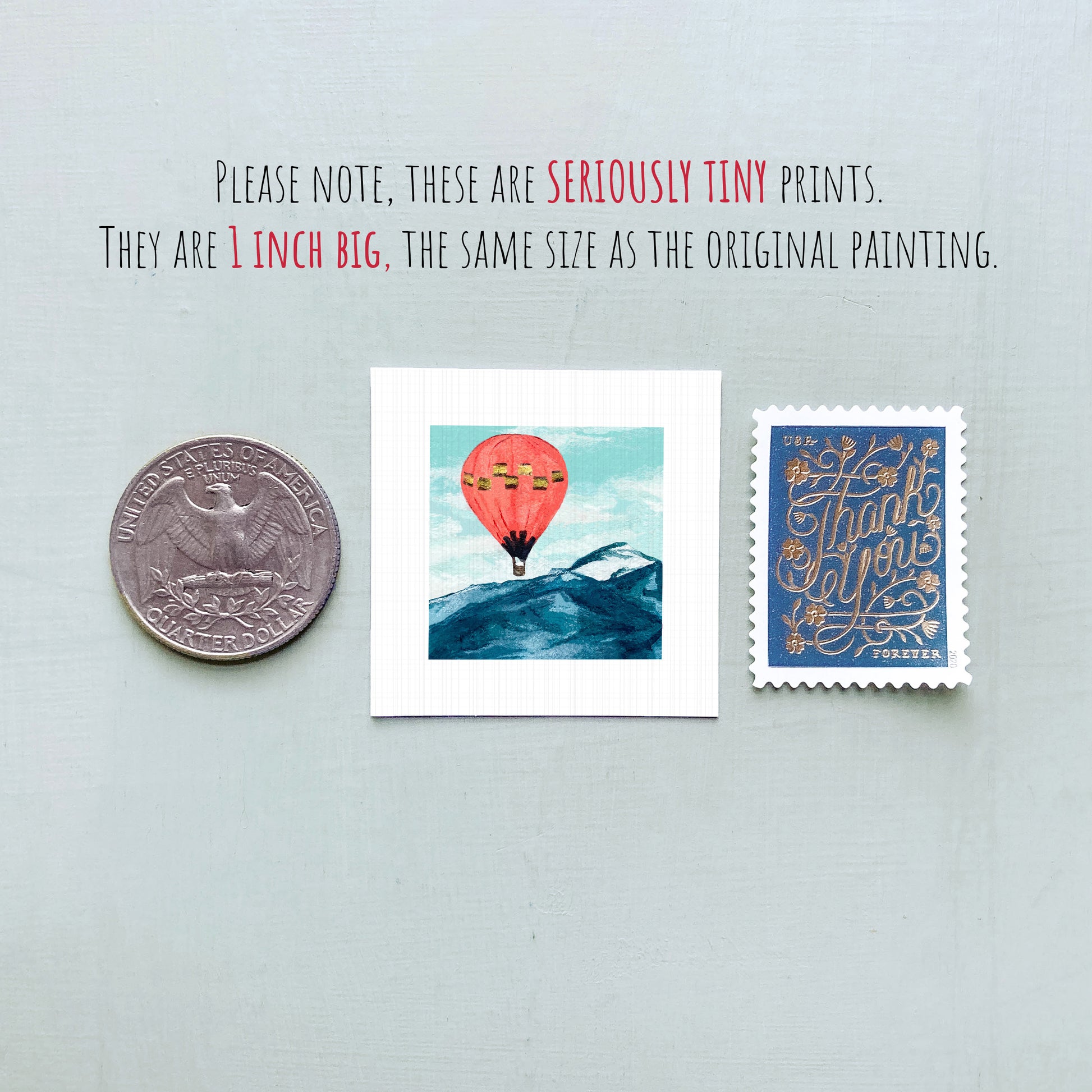 three small prints: a United States quarter, a painting of a hot air balloon over a mountain, and a postage stamp.