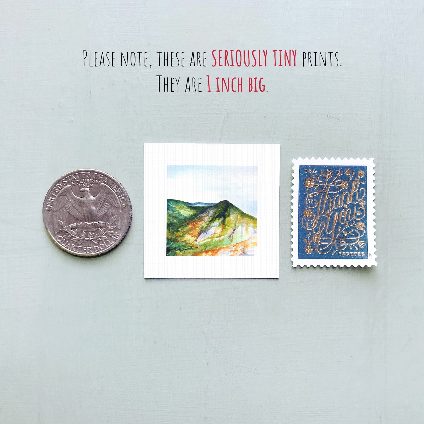 a collection of three small items: a quarter, a postage stamp, and a painting of a mountain landscape.