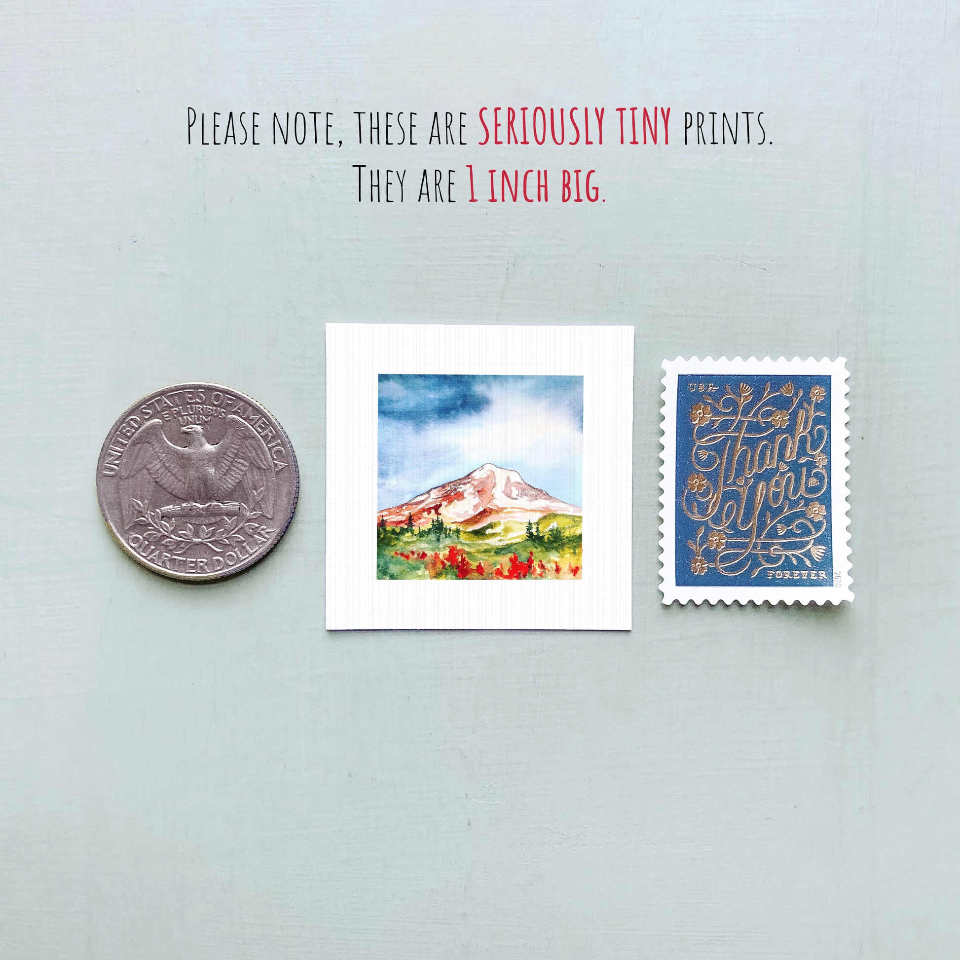 a collection of three small items: a quarter, a watercolor painting of a mountain, and a postage stamp.