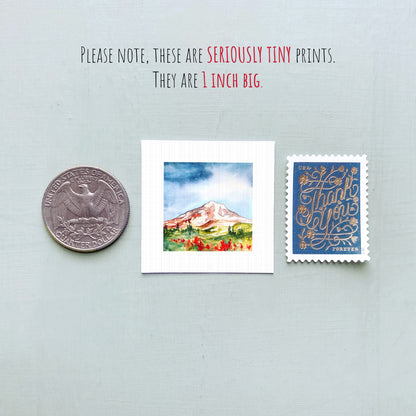 a collection of three small items: a quarter, a watercolor painting of a mountain, and a postage stamp.