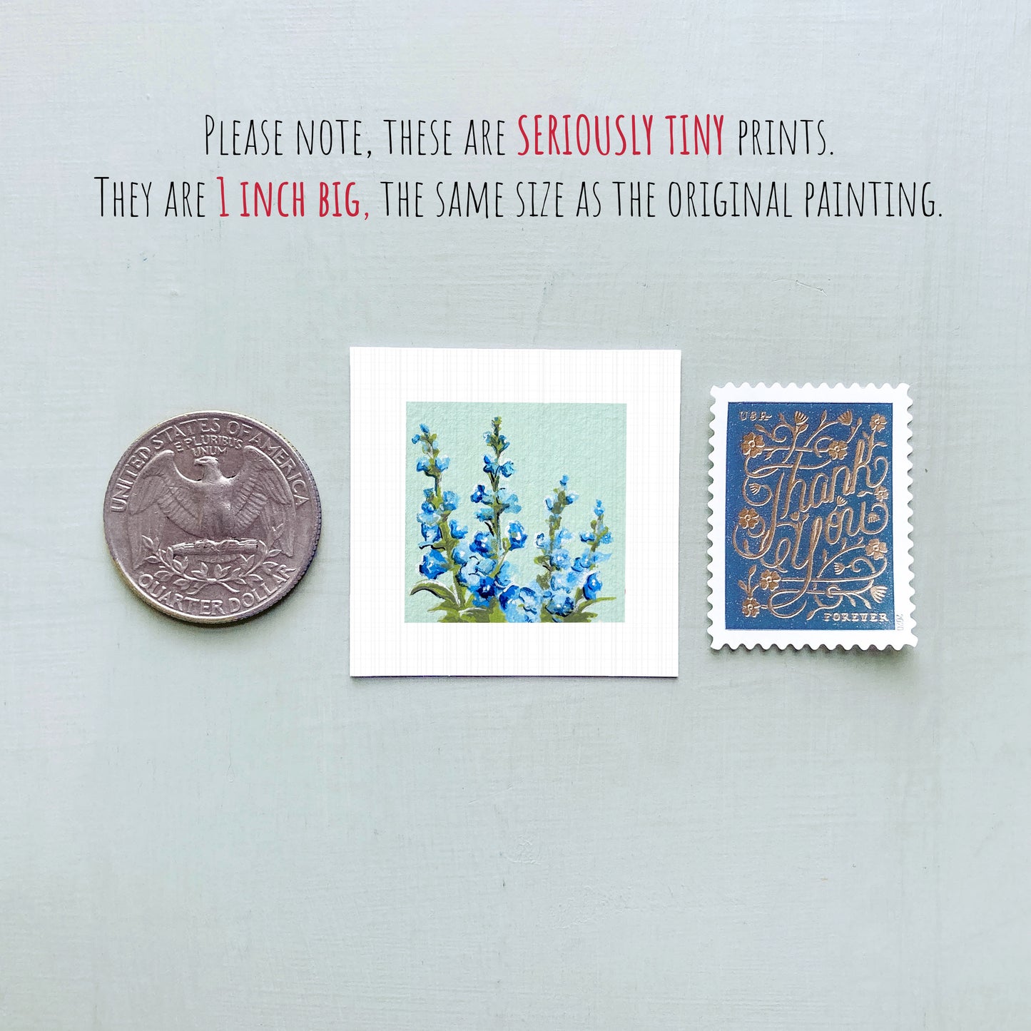 three small artworks: a silver coin, a square print of blue flowers, and a blue postage stamp with gold lettering.