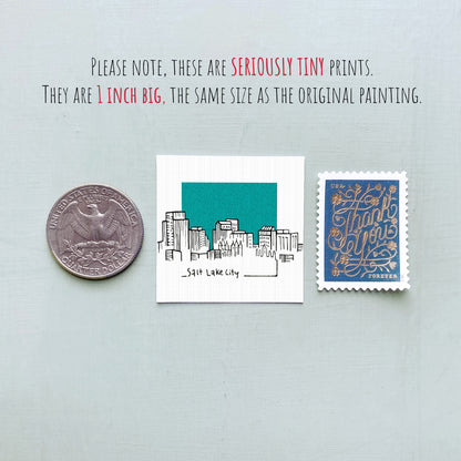 three small prints: a silver coin, a white square with a drawing of a city skyline, and a blue postage stamp with gold lettering.