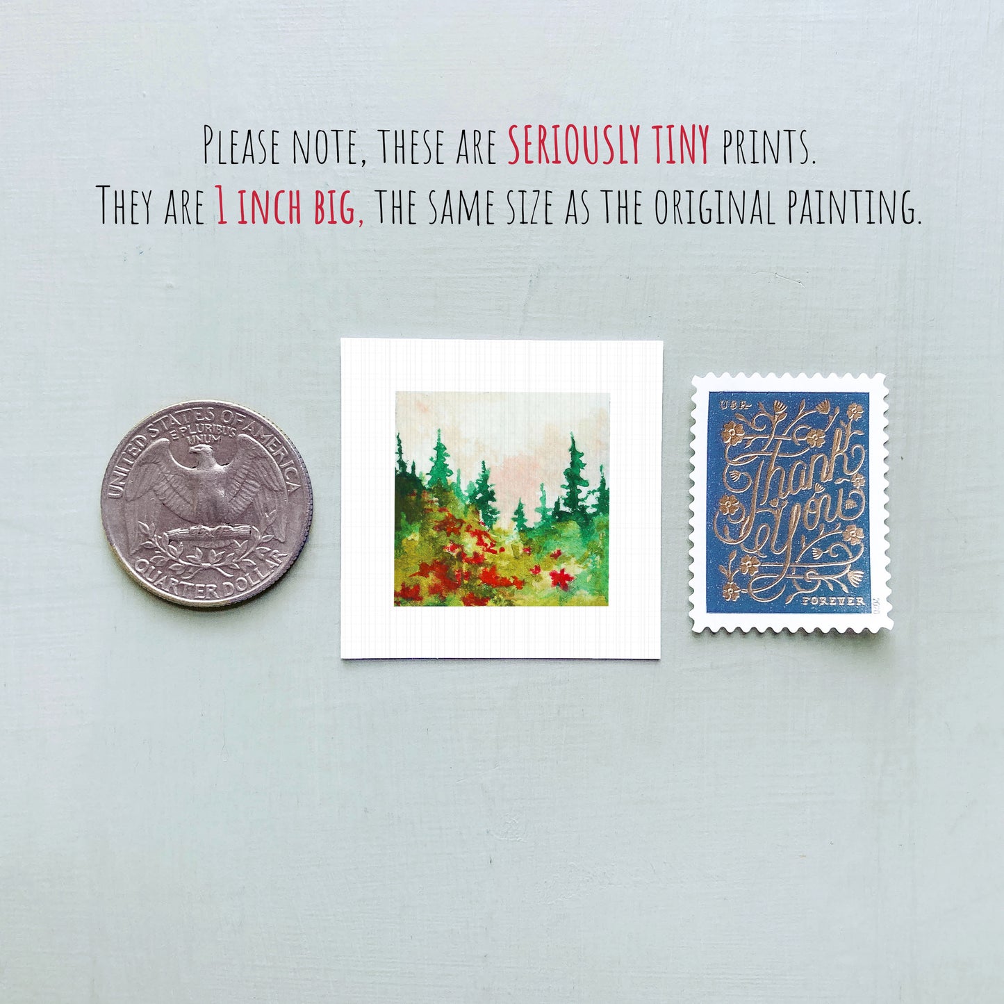 three small prints: a quarter, a square print of a forest scene, and a blue postage stamp with gold lettering.