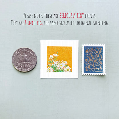 three small artworks: a silver coin, a white square with a floral design, and a blue postage stamp with gold lettering.