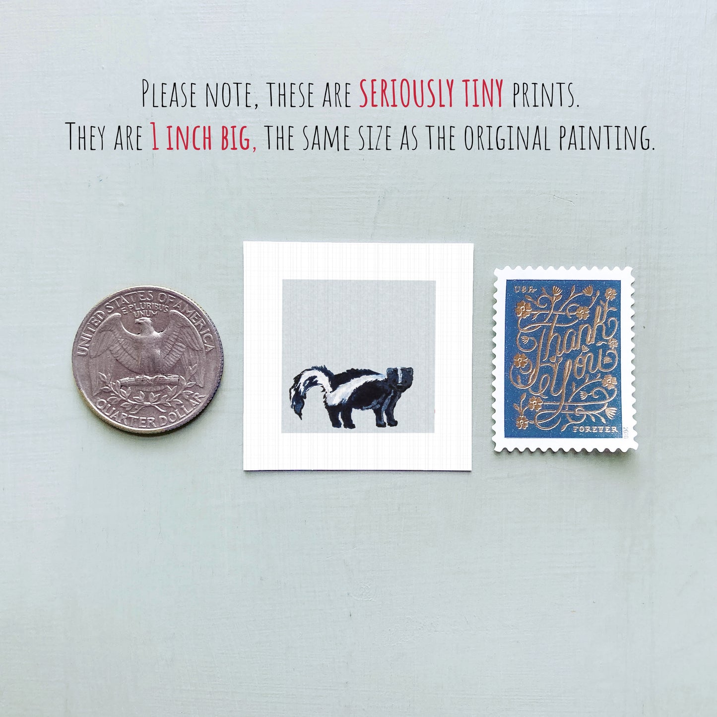 three small items: a quarter, a square print of a black and white animal, and a blue postage stamp with gold lettering.