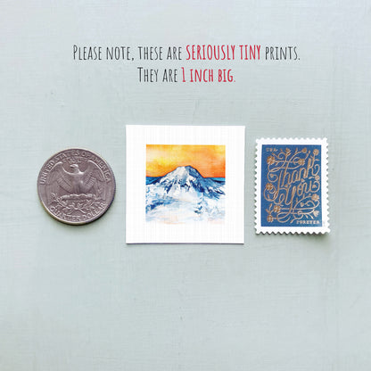 three small prints: a United States quarter, a square print of a mountain landscape, and a blue postage stamp with gold lettering.