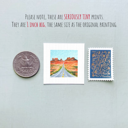 a collection of three small items: a quarter, a miniature painting of a road, and a postage stamp.