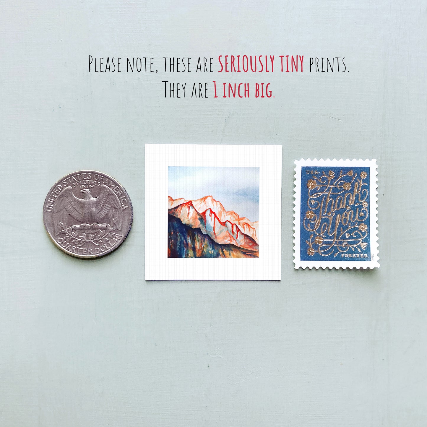 a collection of three small items: a quarter, a postage stamp, and a painting of a mountain landscape.