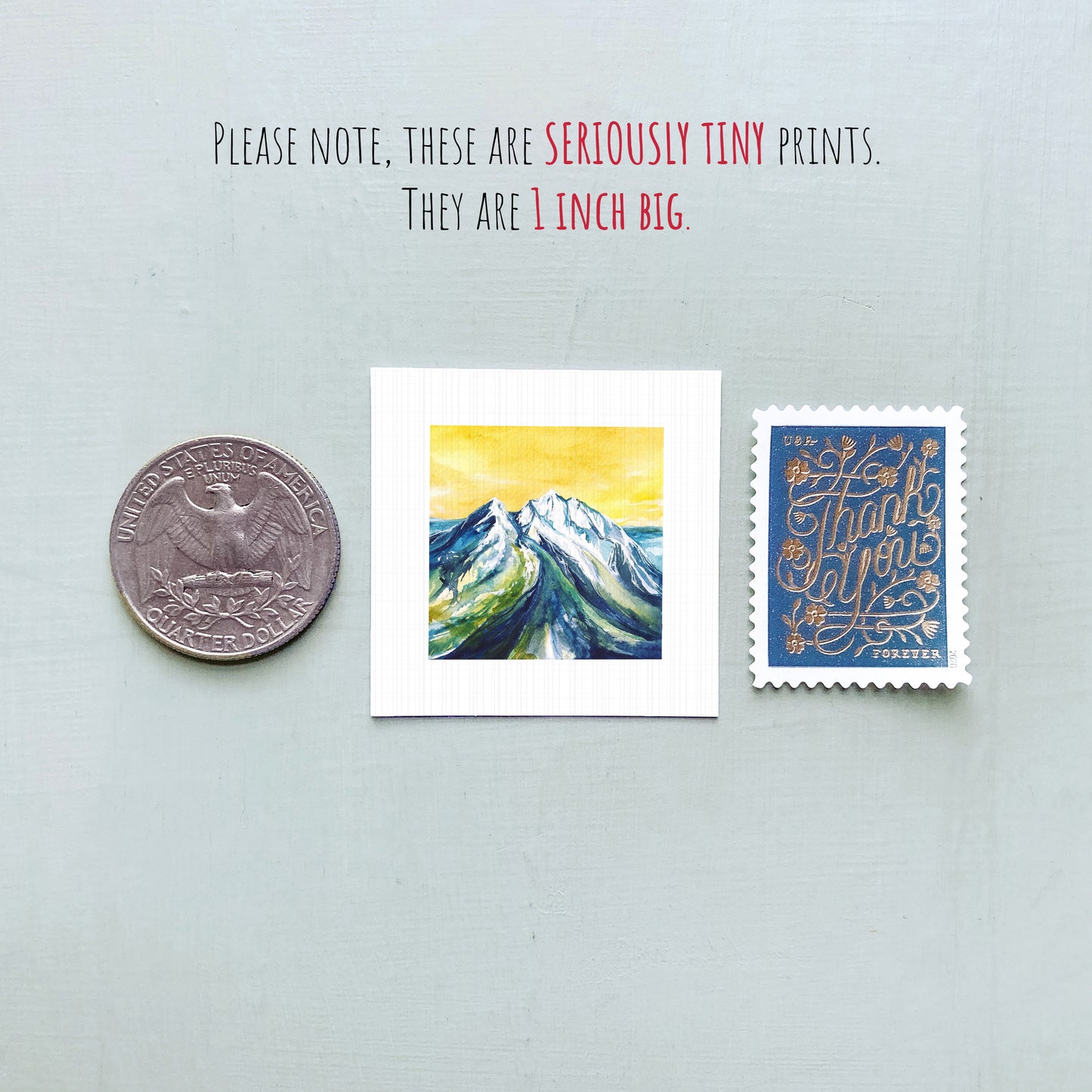 a collection of three small items: a quarter, a postage stamp, and a painting of a mountain landscape.