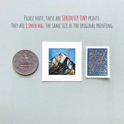 three small prints: a United States quarter, a small square print with a mountain landscape, and a blue postage stamp with gold lettering.