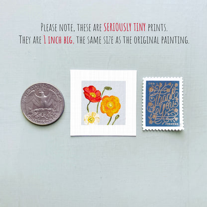 three small prints: a silver coin, a white square print with a red flower, and a blue postage stamp with gold lettering.