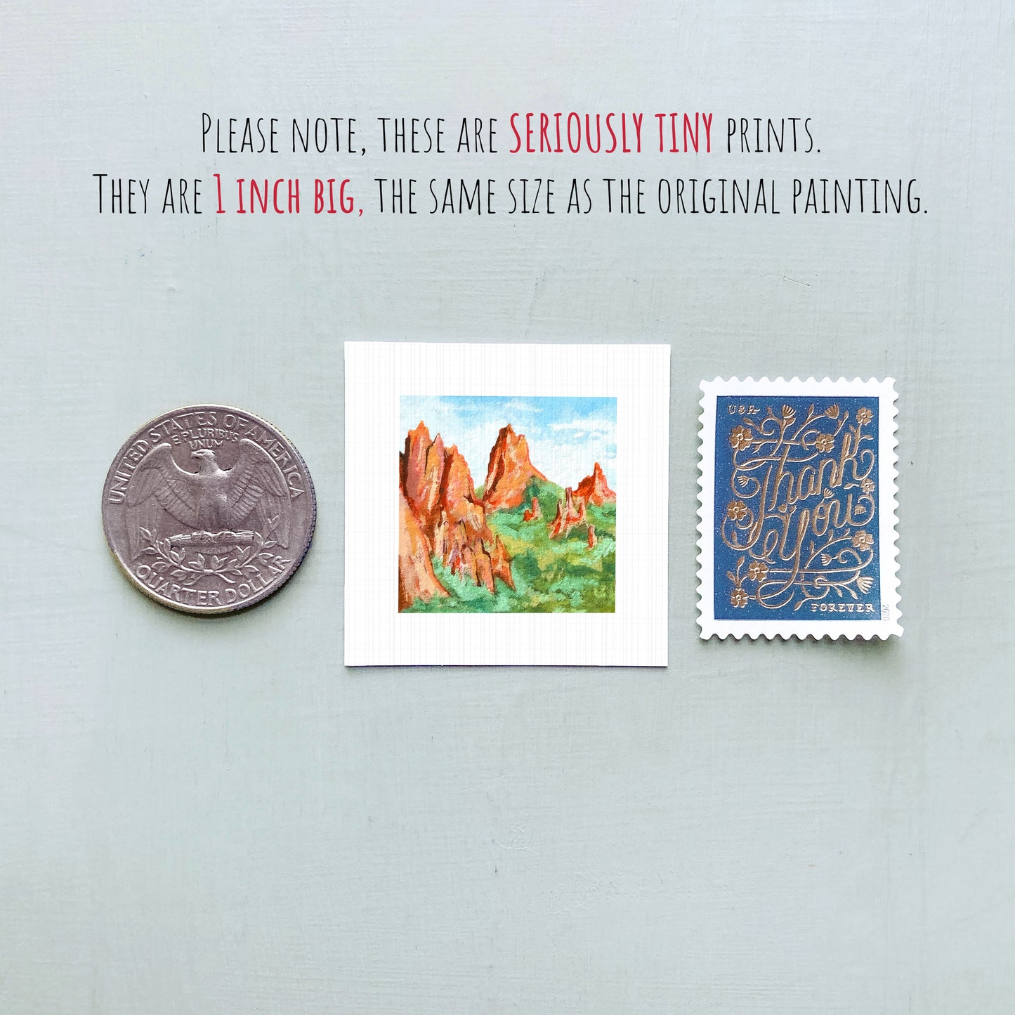 three small prints: a quarter, a postage stamp, and a painting of a mountain landscape.