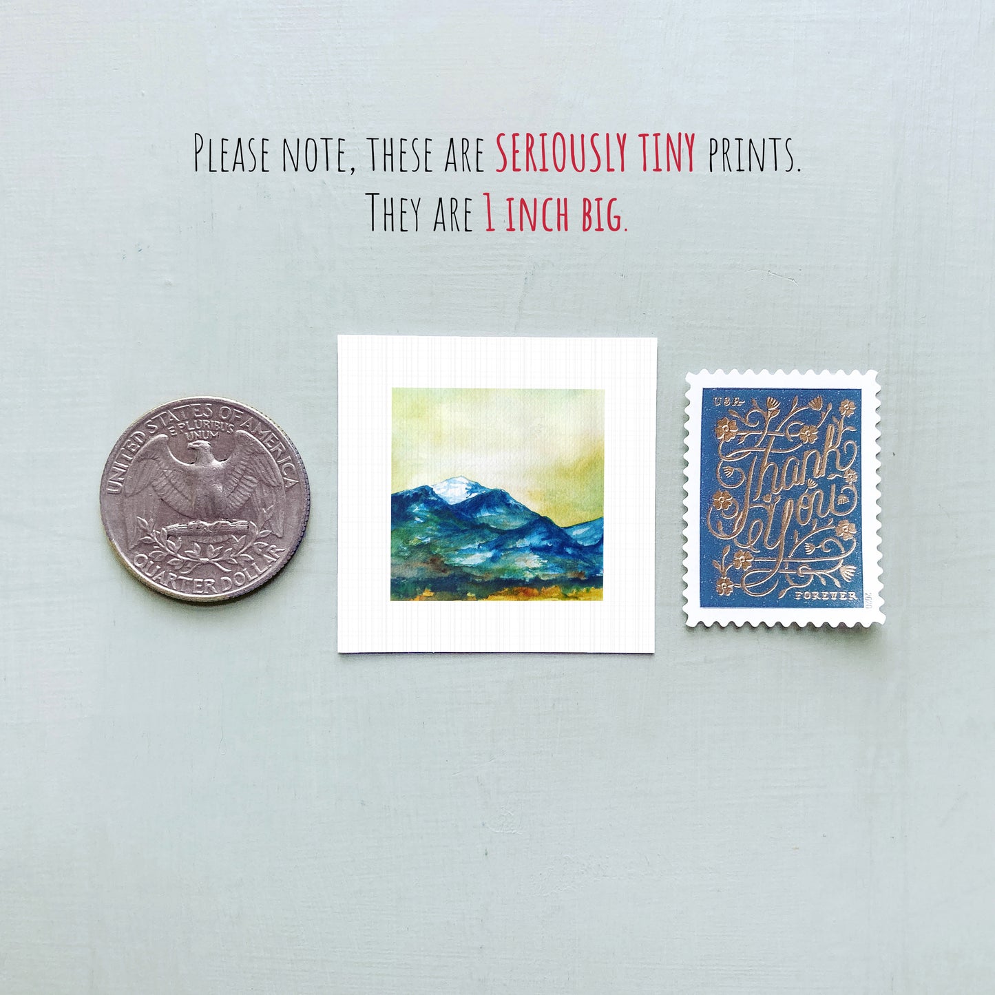 three small prints: a United States quarter, a square print of a mountain landscape, and a blue postage stamp with gold lettering.