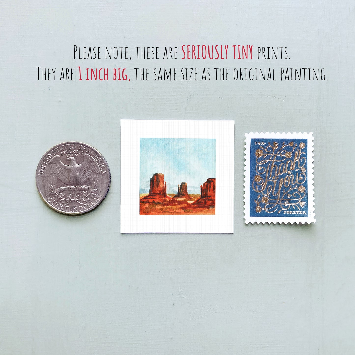 three small prints: a quarter, a square print of a desert landscape, and a blue postage stamp with gold lettering.