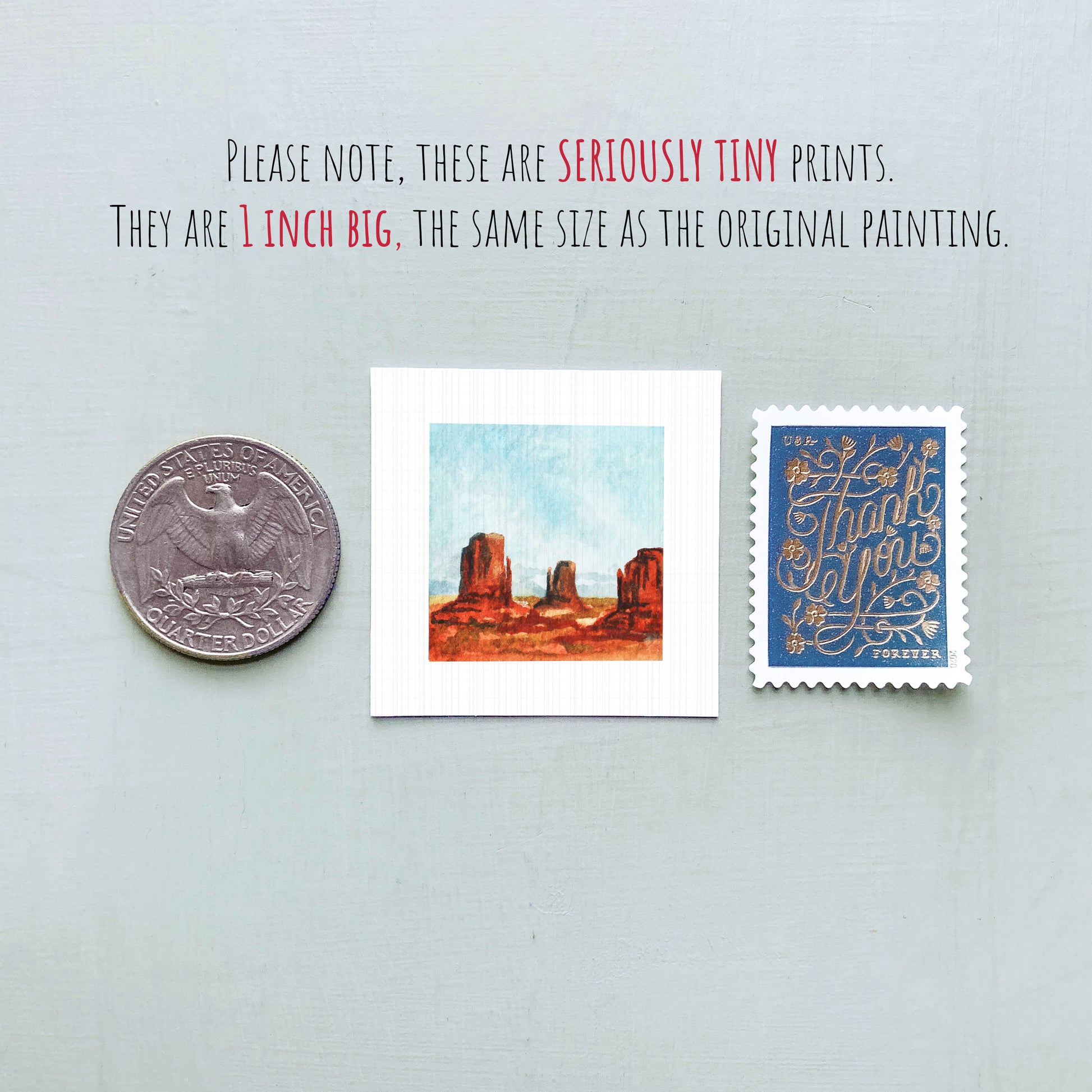 three small prints: a quarter, a square print of a desert landscape, and a blue postage stamp with gold lettering.