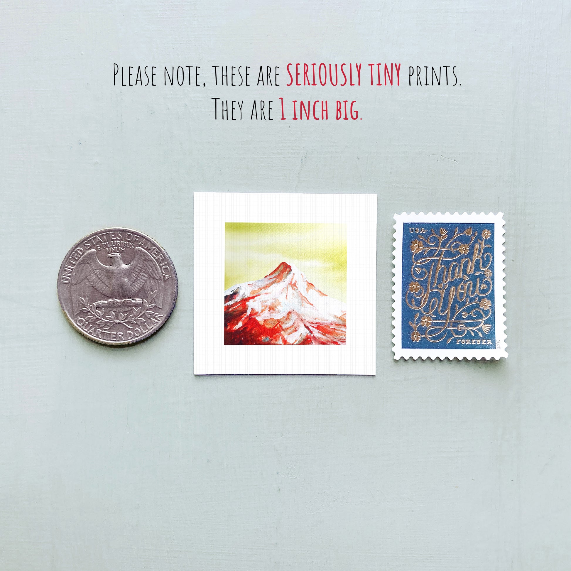 a collection of three small items: a United States quarter, a square print of a mountain, and a blue postage stamp.