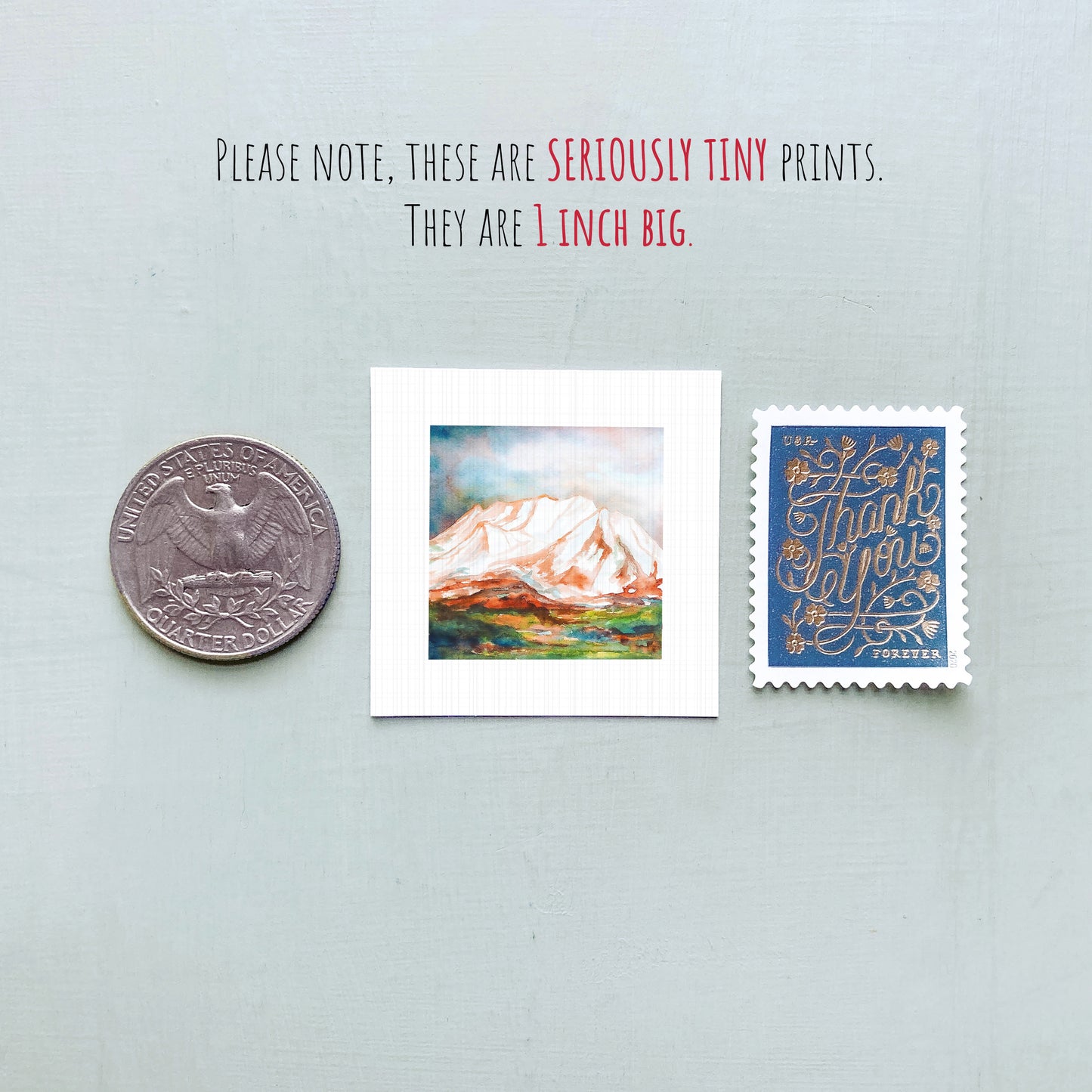 a collection of three small items: a United States quarter, a miniature painting of a mountain, and a postage stamp.