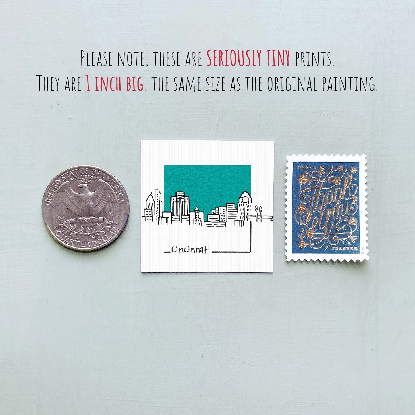 a collection of three small items: a quarter, a piece of paper with a drawing of a city skyline, and a postage stamp.