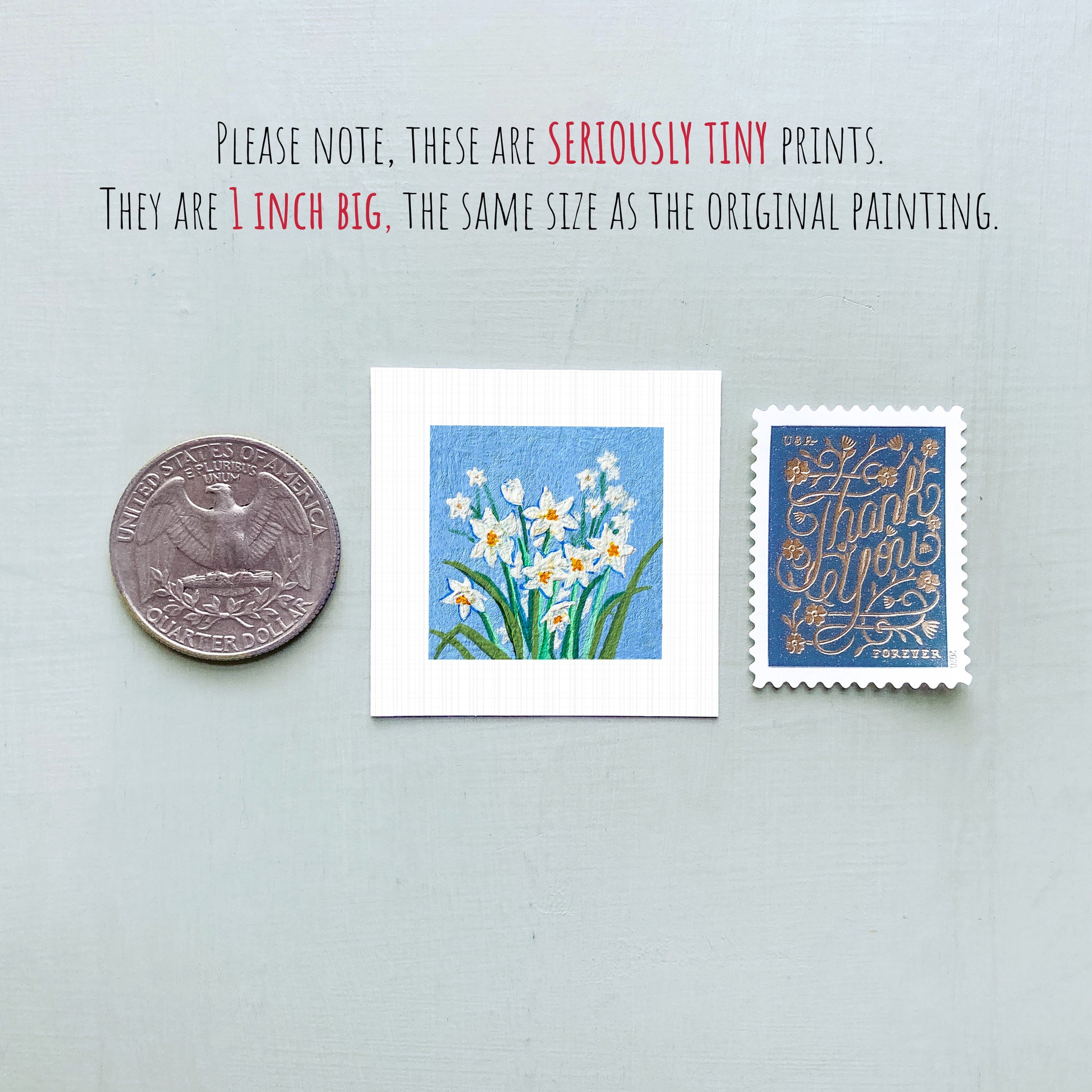 three small artworks: a silver coin, a square print of white flowers, and a blue postage stamp with gold lettering.