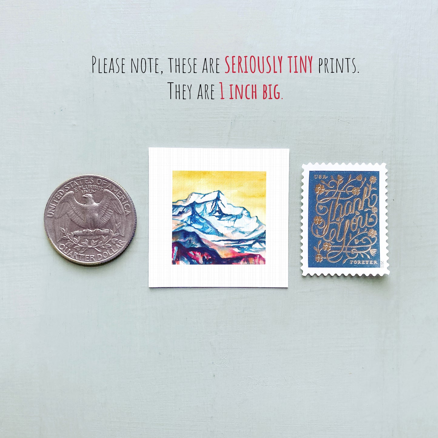 a collection of three small items: a United States quarter, a miniature painting of a mountain, and a postage stamp.