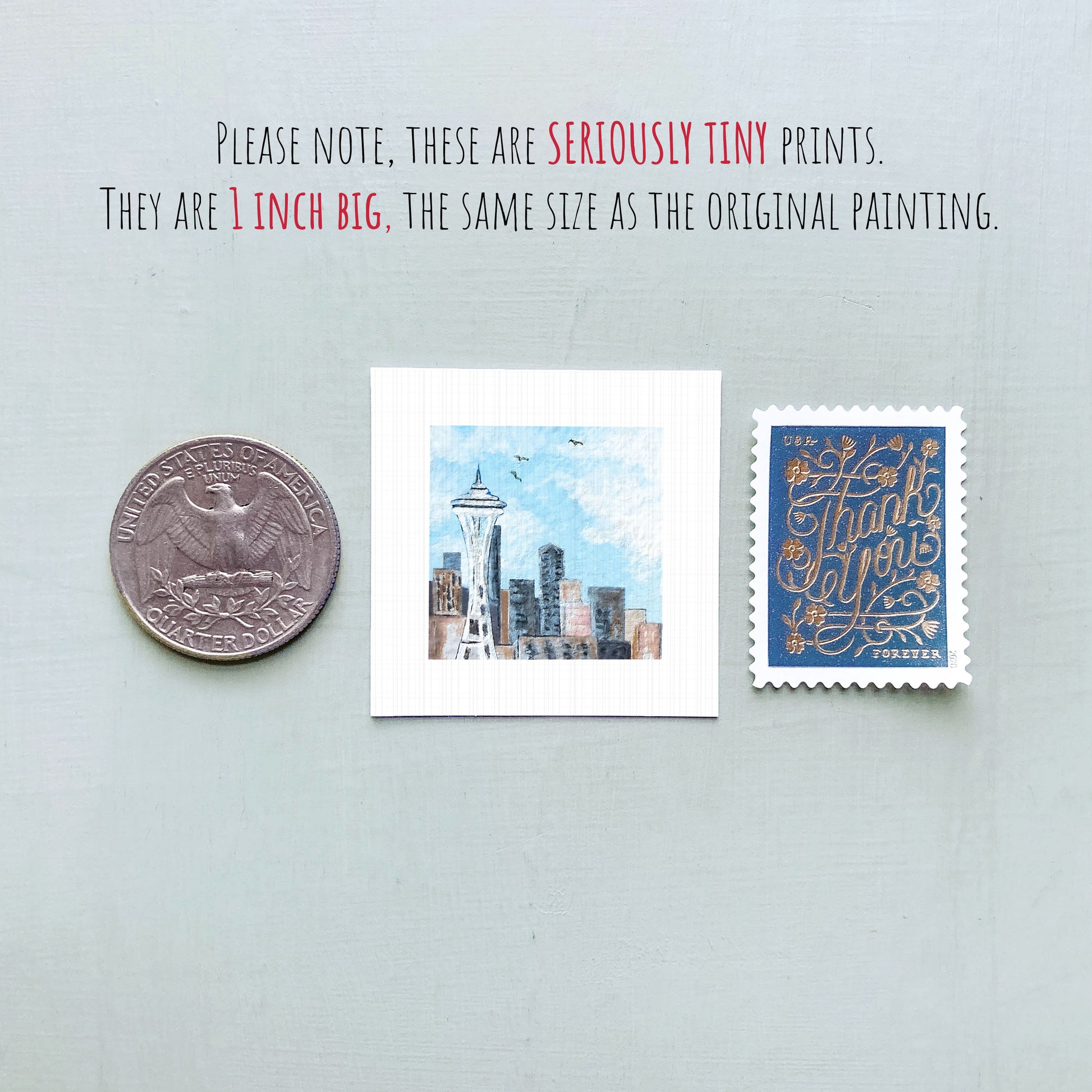 three small prints: a quarter, a postage stamp, and a painting of a city skyline.