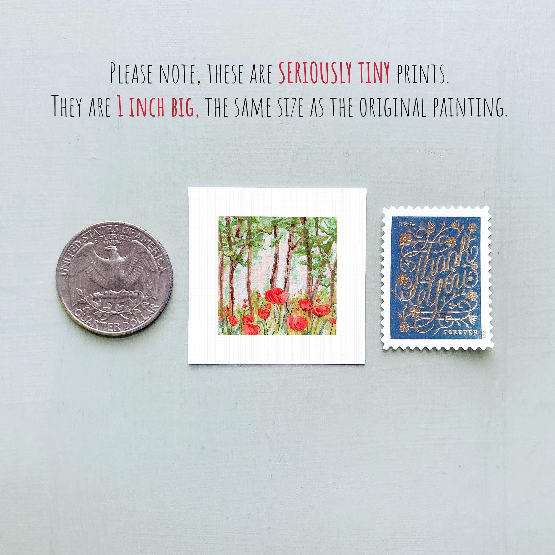 three small artworks: a silver coin, a framed print of a forest scene with red flowers, and a blue postage stamp with gold lettering.