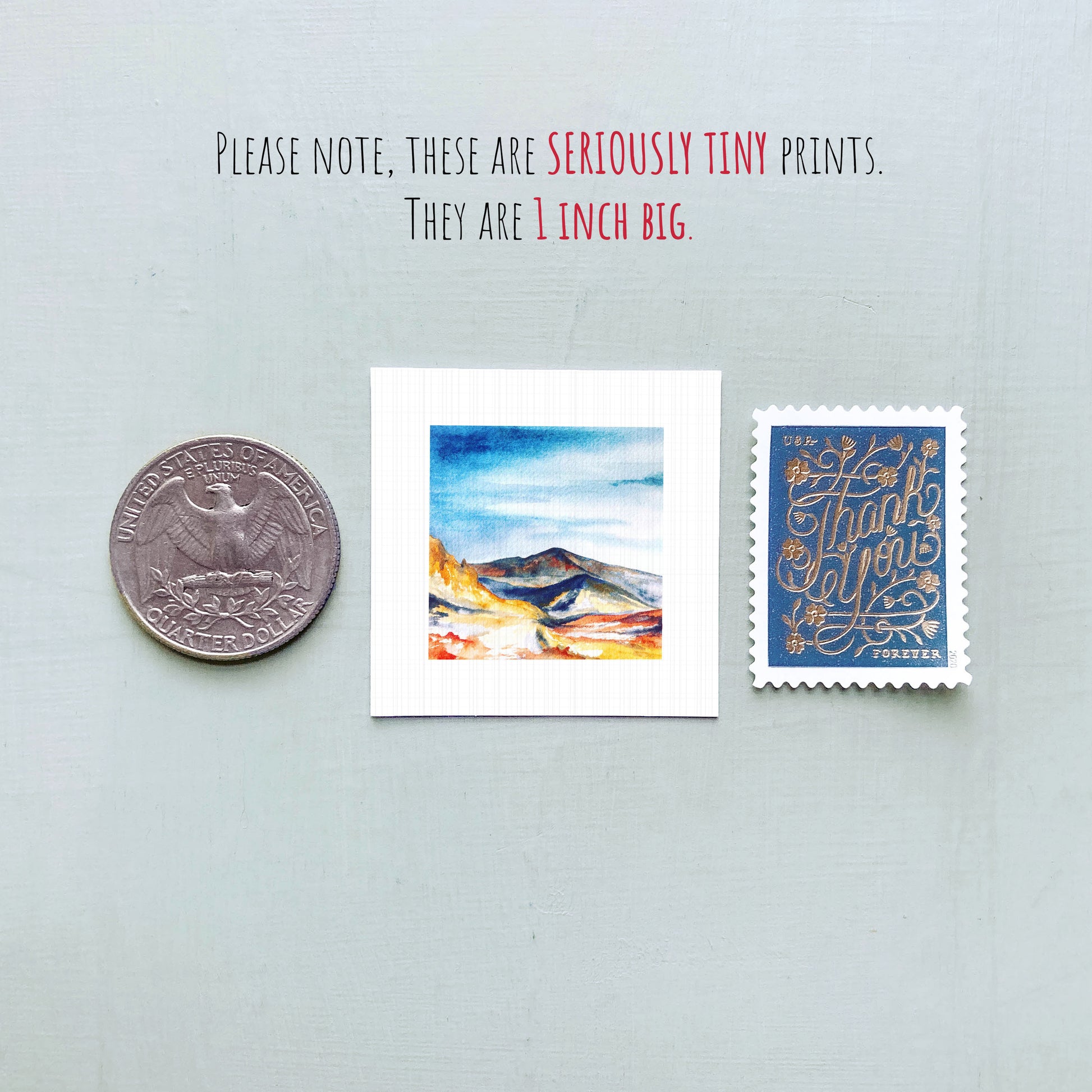 a collection of three small items: a quarter, a watercolor painting of a mountain landscape, and a postage stamp.
